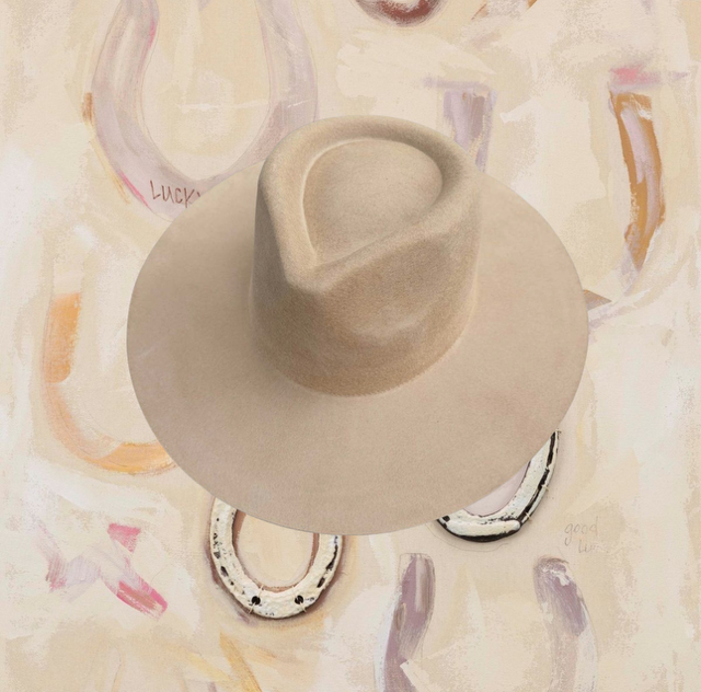 A beige hat photographed over a painted horseshoe backdrop