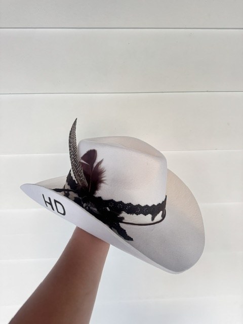 A white hat with black embellishments and feathers, indoor light