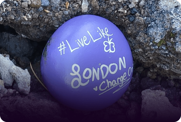 A purple painted rock that reads "#LiveLike LONDON · Charge On."